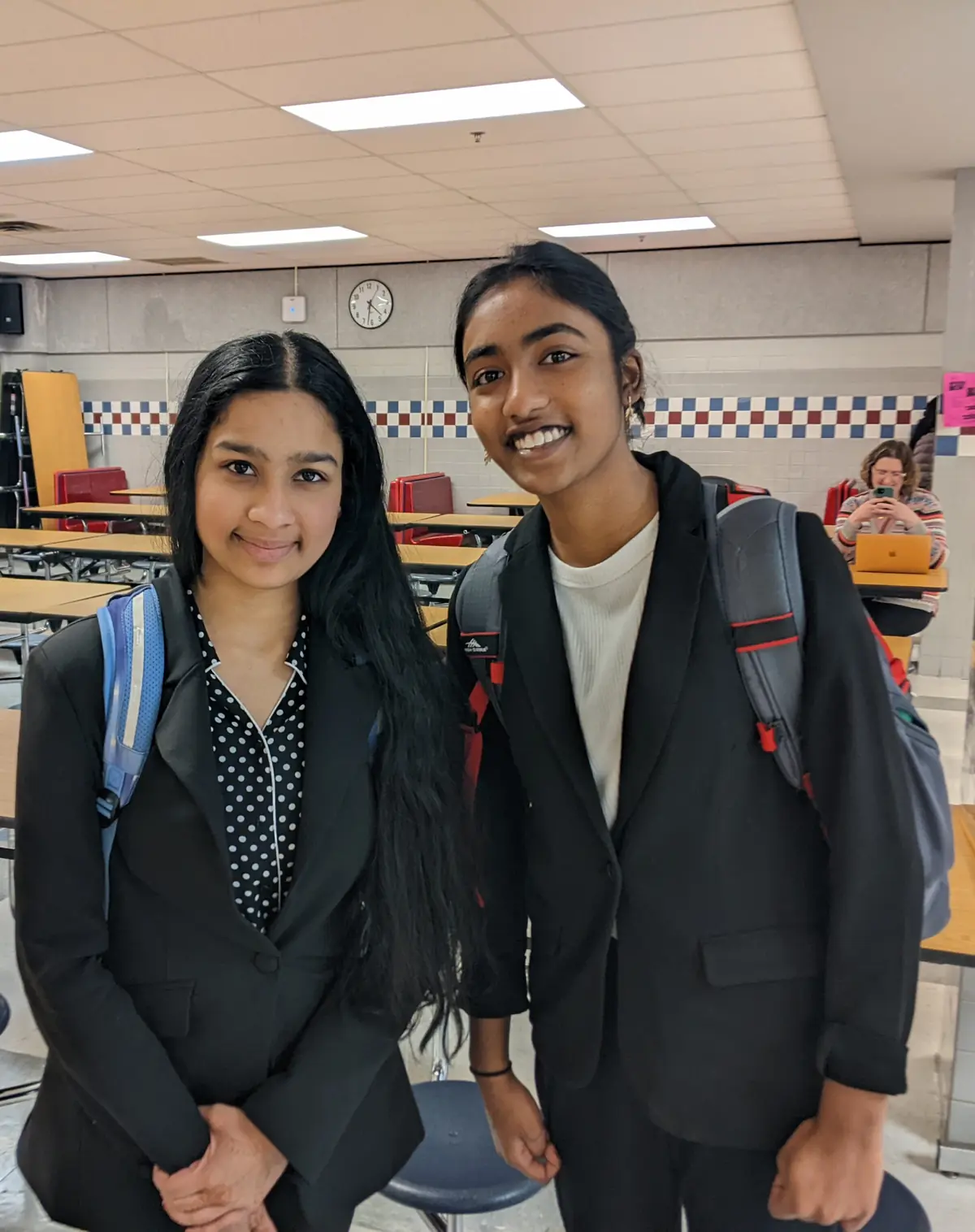 Two students in tournament dress smiling in a school cafeteria